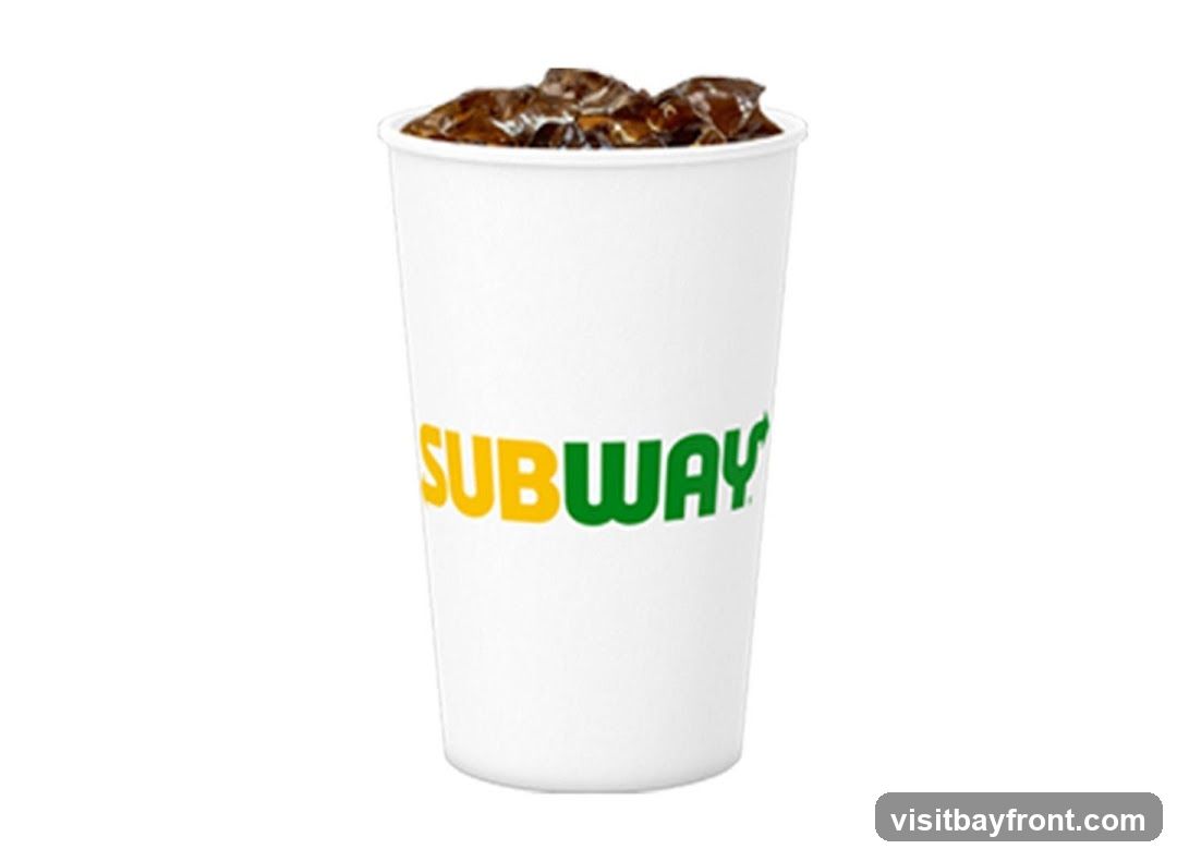 A white paper cup with the Subway logo printed in yellow and green. The cup is filled with a dark beverage and ice.
