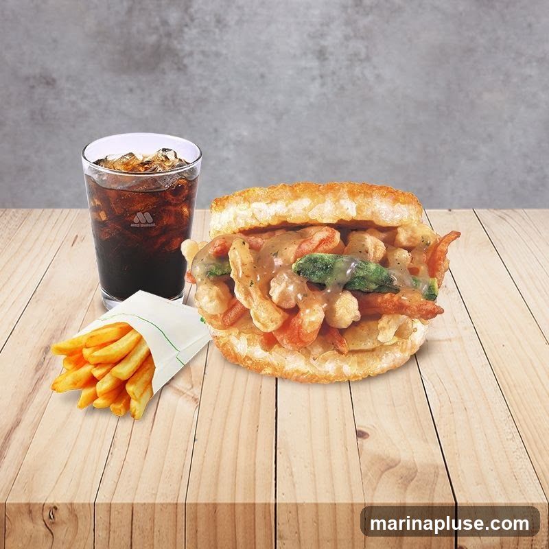 A close-up shot of a burger filled with fried seafood and vegetables, served with a side of french fries and a glass of cola with ice. The food is arranged on a wooden table against a textured gray background.