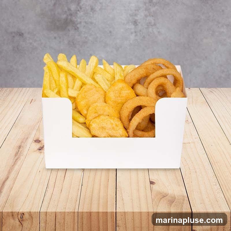 A white paper container filled with french fries, chicken nuggets, and onion rings sits on a wooden table. The background is a textured gray wall.