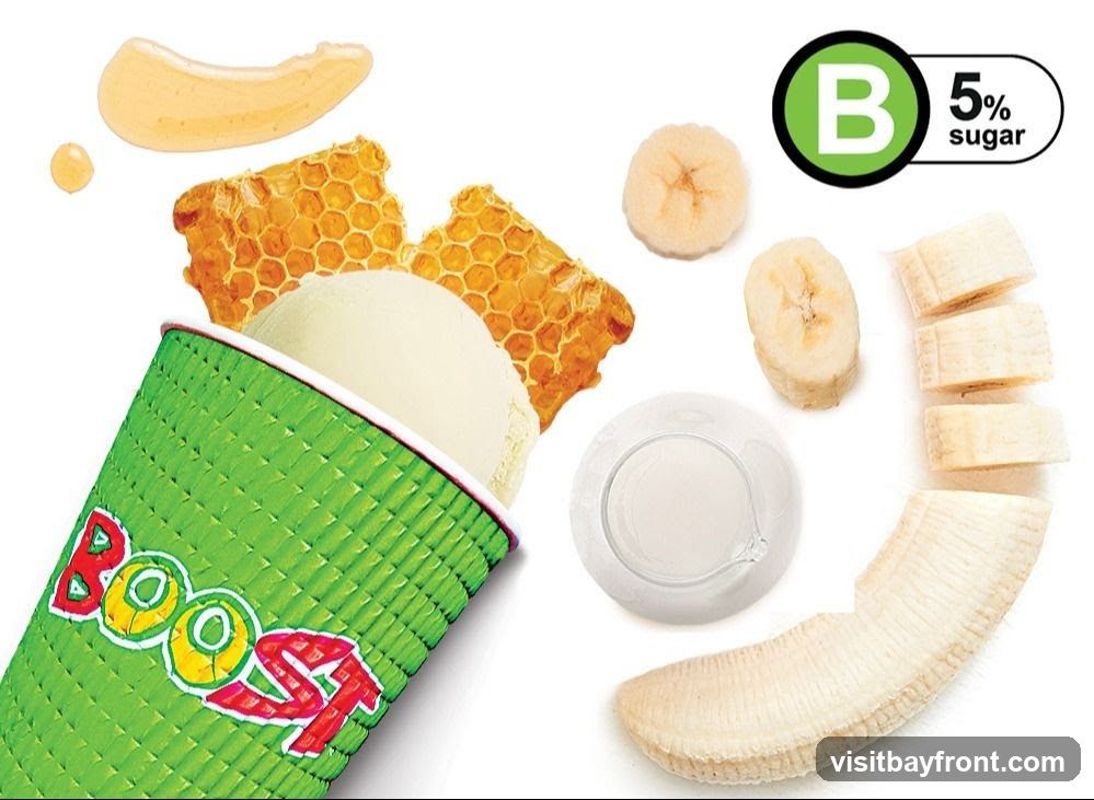 A green cup with the word "BOOST" in colorful letters is filled with a scoop of light-colored ice cream. Beside the cup are pieces of honeycomb, a drizzle of honey, sliced bananas, and a small white dish. A green circle with a white "B" and the text "5% sugar" is in the upper right corner.