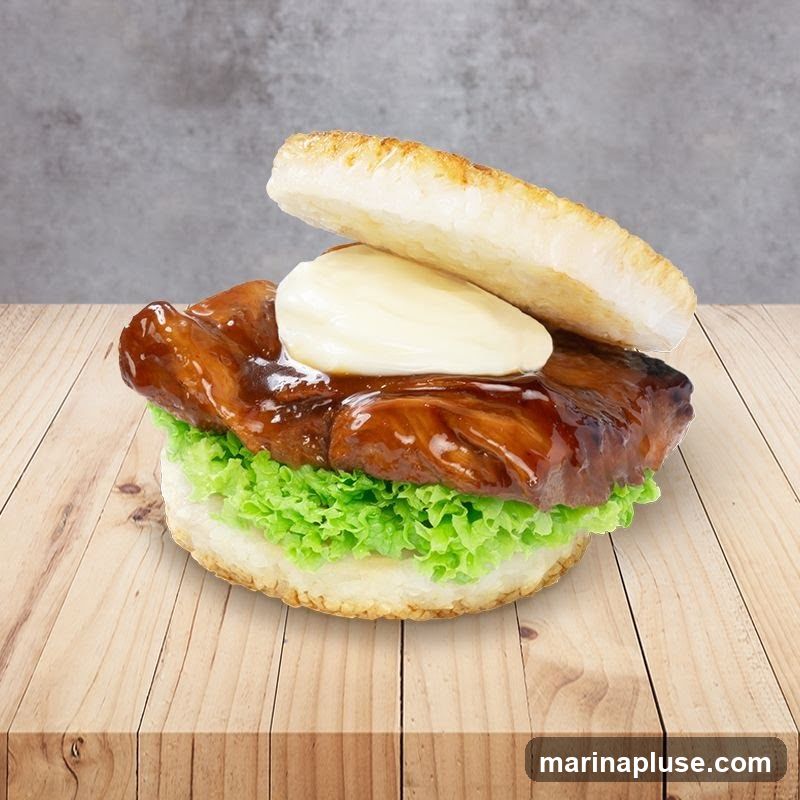 A teriyaki chicken burger with lettuce and mayonnaise on a wooden table.