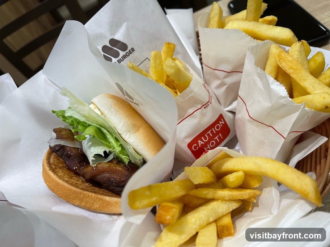 Four golden-brown fried mantou buns are arranged on a white rectangular plate with a white napkin. To the right of the buns, a white ramekin holds a savory dip with visible chunks of food, possibly meat or seafood, in a reddish-orange sauce. The plate and ramekin are set on a light-colored wooden surface, with a textured gray background behind.