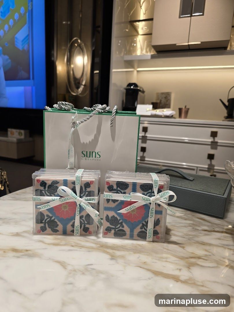 Two sets of coasters, each wrapped in clear plastic and tied with a ribbon featuring the brand name