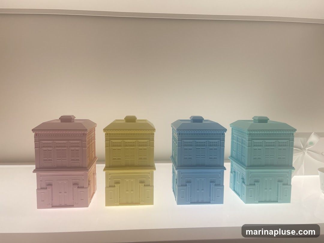 Four decorative boxes are displayed in pastel colors: pink, yellow, blue, and green. Each box is designed to resemble a two-story building with architectural details like windows and doors. They are arranged in a row on a white surface under soft lighting.