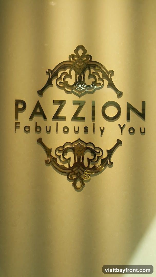 A golden logo with ornate scrollwork above and below the text "PAZZION" and "Fabulously You". The background is a textured, muted gold color with soft shadows.