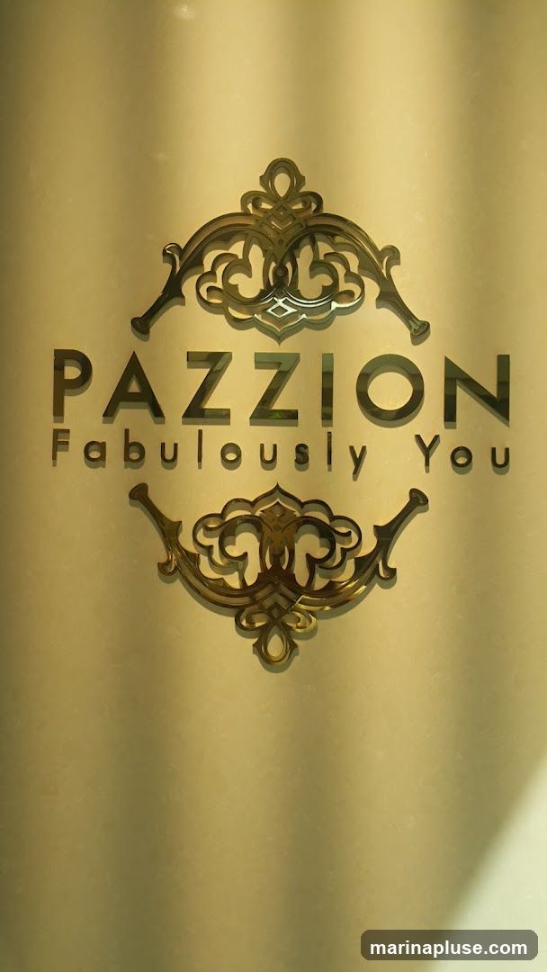 A golden logo with ornate scrollwork above and below the text "PAZZION" and "Fabulously You". The background is a textured, muted gold color with soft shadows.