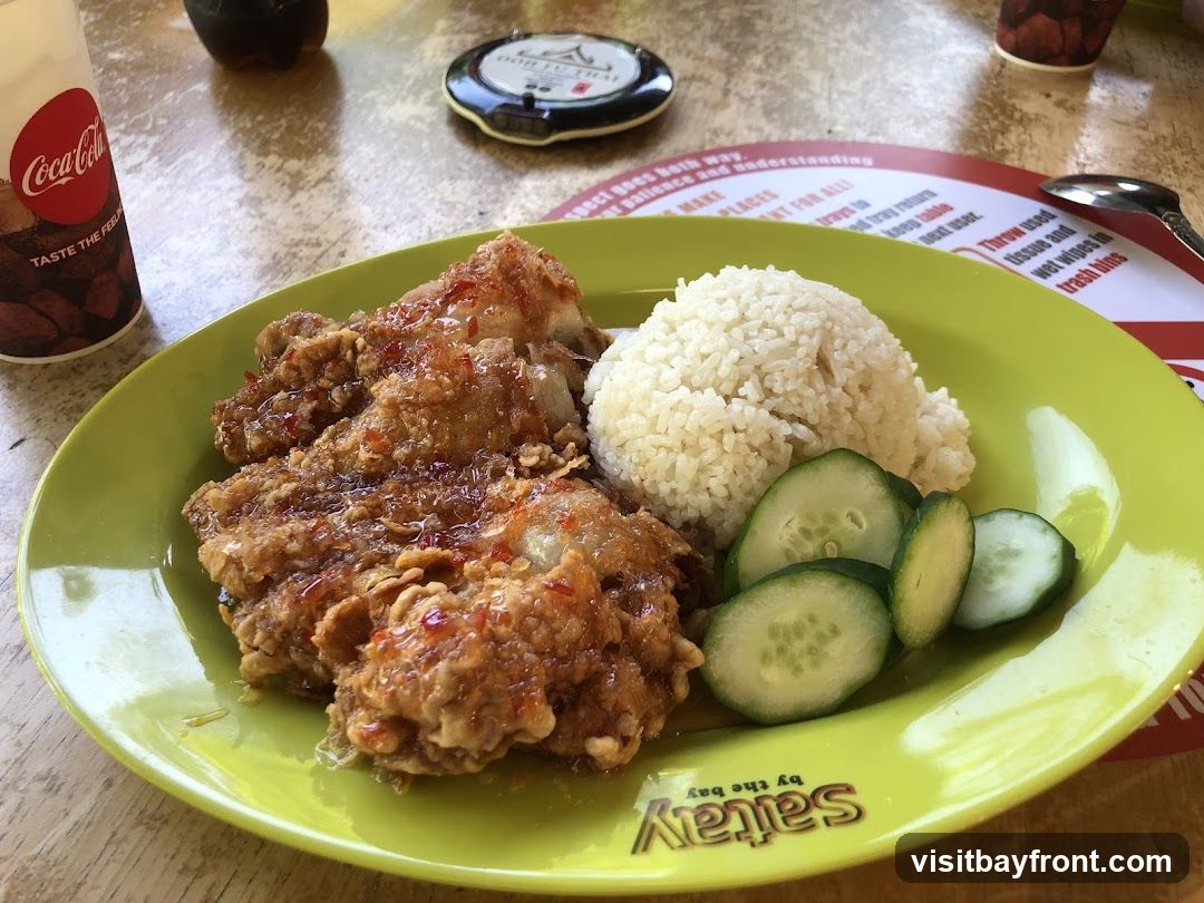 A plate of fried chicken with a side of rice and sliced cucumbers, served on a lime green plate. A Coca-Cola cup is visible to the left. A placemat with instructions is under the plate.