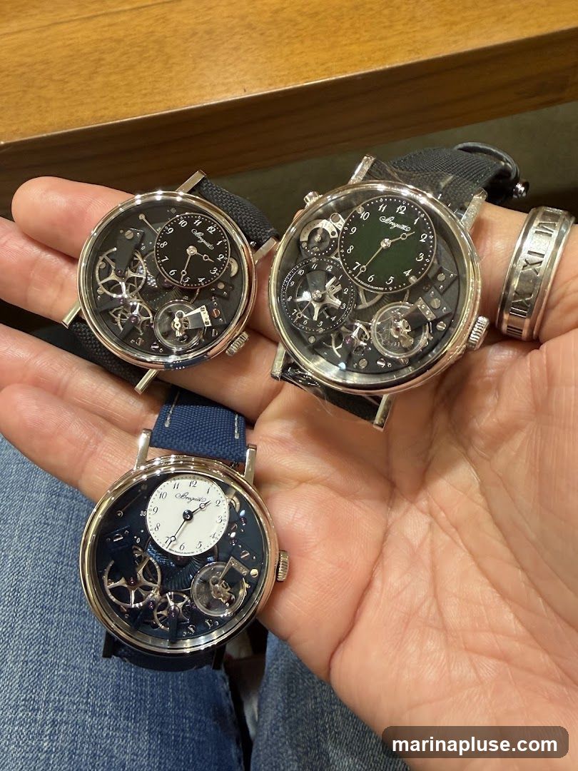 A hand holds three skeletonized luxury watches. The watch on the left has a black dial with visible gears and a small sub-dial. The watch in the center has a green sub-dial and intricate mechanical details. The watch on the bottom has a white sub-dial and a dark blue base with visible gears. A ring with Roman numerals is also visible on the ring finger.