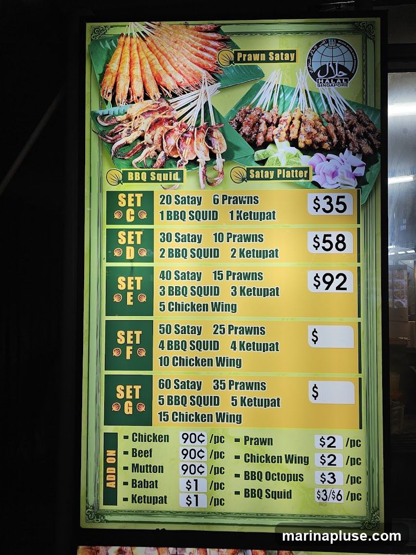A menu board displaying various satay sets and add-on items. The sets include combinations of satay, prawns, BBQ squid, and chicken wings, with prices ranging from $35 to $92. Add-on items include chicken, beef, mutton, babat, ketupat, prawns, chicken wings, BBQ octopus, and BBQ squid with individual prices.