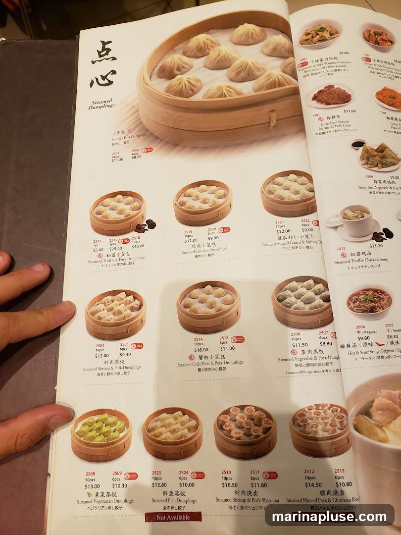 A menu page featuring various types of steamed dumplings, with images and descriptions in English and Japanese.