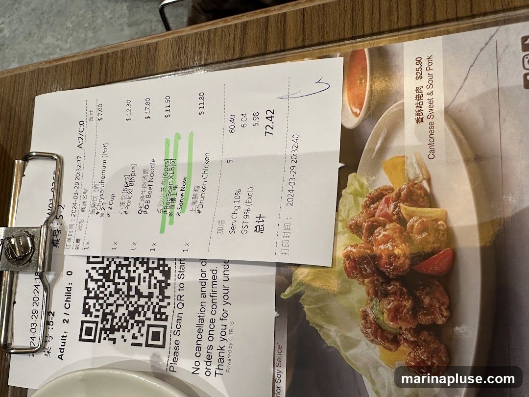 A close-up of a restaurant bill with a QR code and a picture of a food item. The bill lists several items with prices, including Chrysanthemum tea, Pork XLB, Beef Noodle, Red Bean XLB, and Drunken Chicken. It also shows service charge and GST. The food item pictured is Cantonese Sweet & Sour Pork.