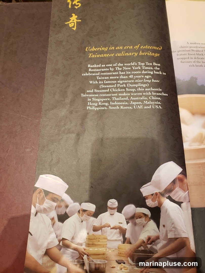 A page from a menu or brochure describing a Taiwanese restaurant's heritage. It highlights its ranking as one of the world's Top Ten Best Restaurants by The New York Times and its 40-year history. The signature dishes mentioned are xiao long baos (Steamed Pork Dumplings) and Steamed Chicken Soup. The restaurant has branches in multiple countries. The image also features a photograph of chefs preparing dumplings.