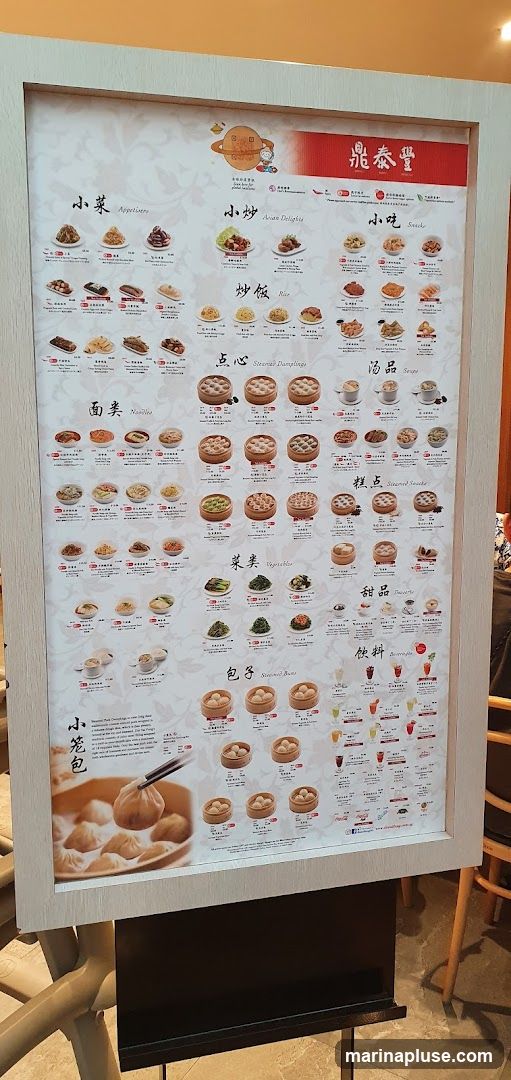 A menu board displaying various Chinese dishes categorized into Appetizers, Asian Delights, Snacks, Rice, Noodles, Steamed Dumplings, Soups, Vegetables, Steamed Buns, Desserts, and Beverages.