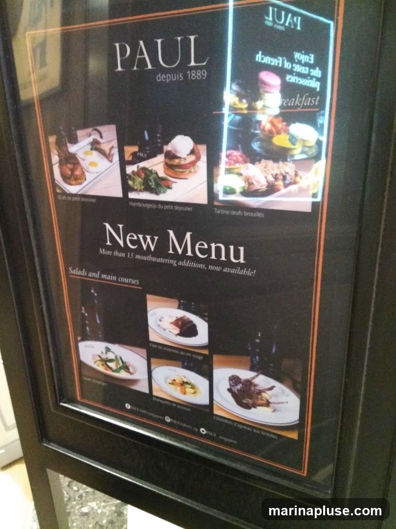 A menu board for PAUL, a bakery and restaurant established in 1889. The menu features breakfast items and salads/main courses, with images of dishes.