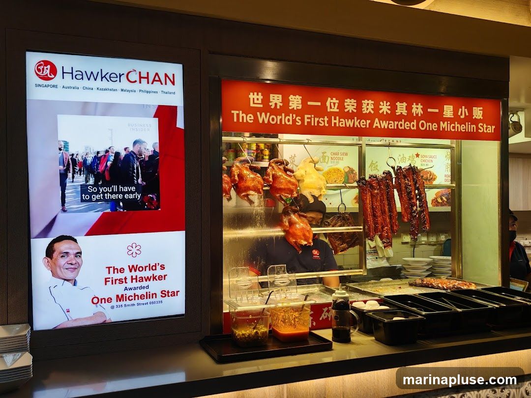 A food stall with roasted chickens and ribs hanging, and a display of menu items. A screen shows a Business Insider article about the stall and its founder.