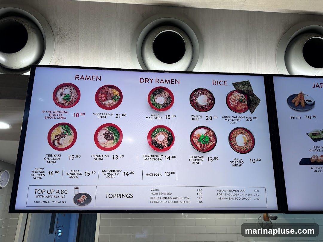 A digital menu board displaying various ramen dishes, dry ramen, rice bowls, and Japanese appetizers.