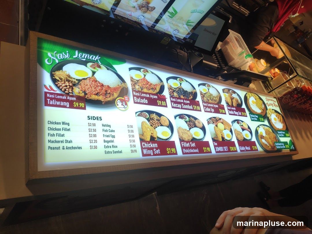 A brightly lit menu board displaying various Nasi Lemak dishes and sides.