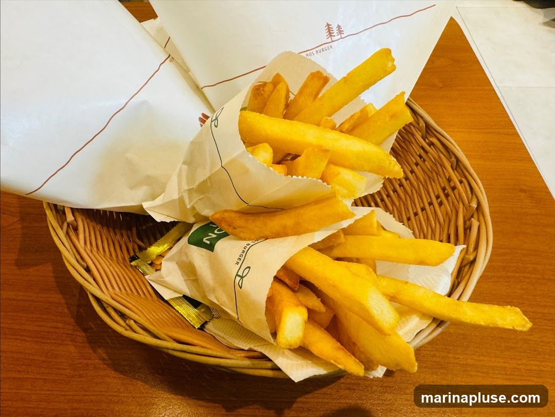 A basket filled with french fries, served in paper wrappers. The wrappers have branding that includes the text "MOS BURGER" and a tree logo.