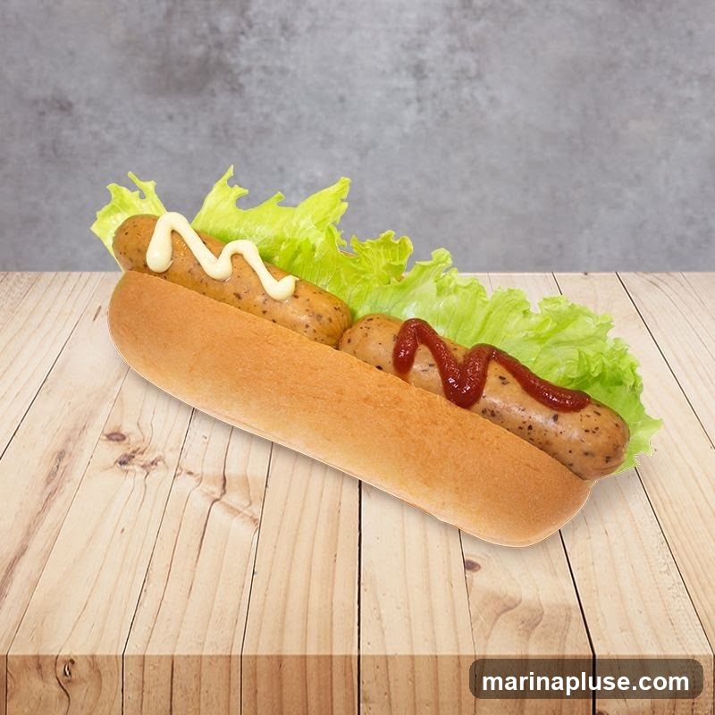 A close-up shot of a hot dog in a bun, topped with lettuce, mayonnaise, and ketchup, resting on a wooden surface against a textured gray background.