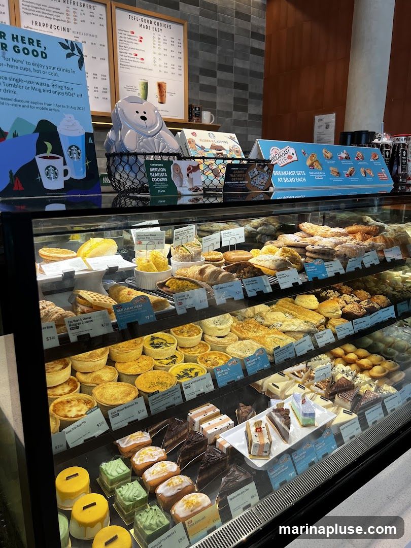 A display case filled with various pastries, cakes, and savory items. In the background, there are menu boards and promotional signs.