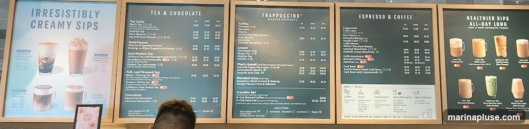 Multiple menu boards displaying various beverages including creamy sips, tea and chocolate drinks, Frappuccinos, espresso and coffee, and healthier sips.
