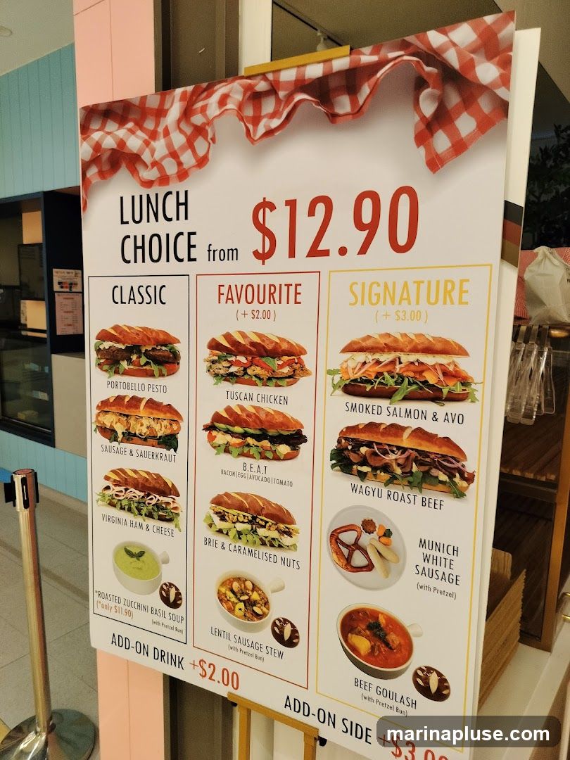 A menu board displaying lunch choices with three categories: Classic, Favourite, and Signature. The base price is $12.90, with add-on options for drinks and sides.