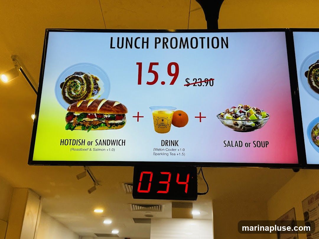 A digital menu board displaying a lunch promotion with a hotdish or sandwich, a drink, and a salad or soup. The original price was $23.90, now on promotion for $15.9.