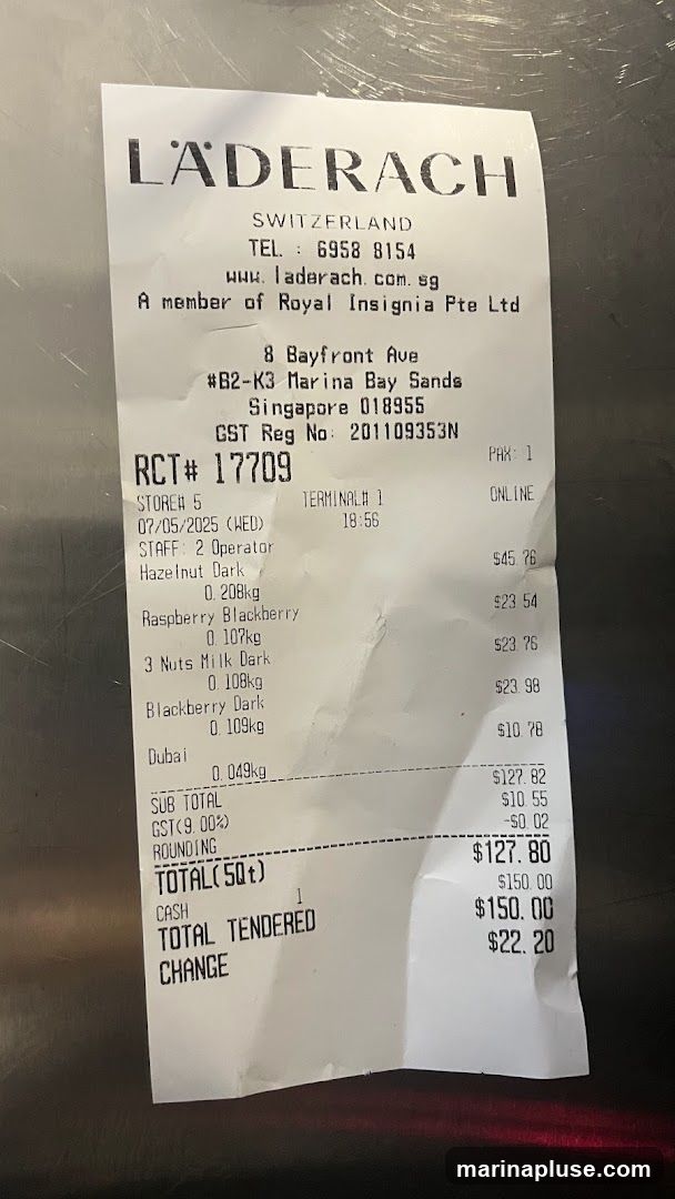 A receipt from Laderach, a Swiss chocolatier, detailing a purchase of various chocolate items. The receipt includes the store's contact information, transaction details, and a breakdown of the items purchased, including weights and prices. The total amount tendered was $150.00, with a change of $22.20.