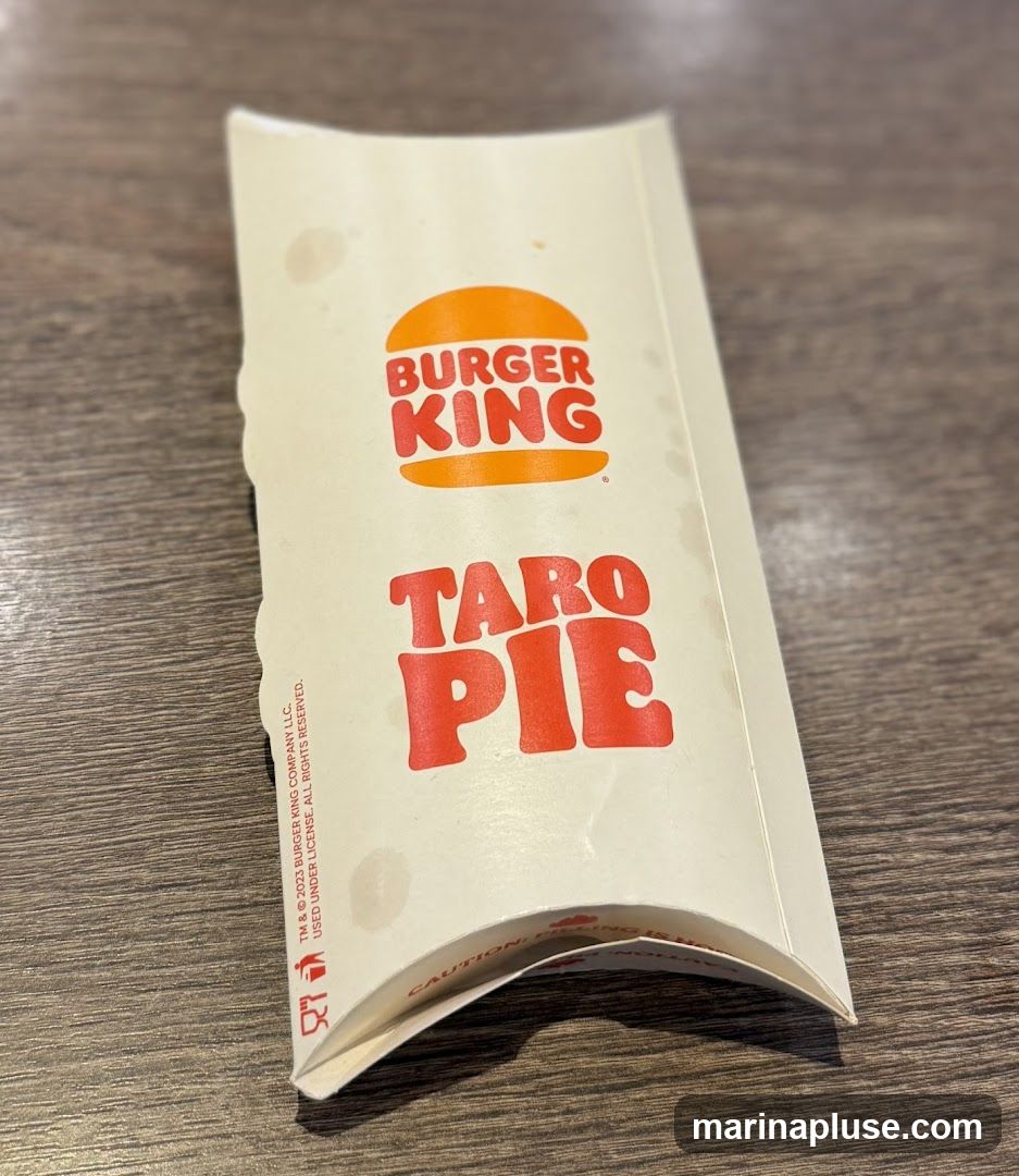 A close-up shot of a Burger King branded packaging for a Taro Pie. The packaging is light-colored with the Burger King logo and the words "TARO PIE" printed in red. There are some smudges on the packaging.