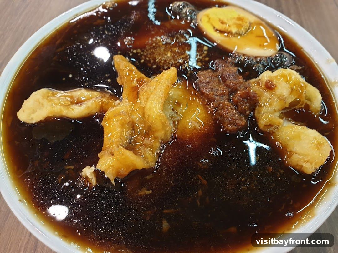 A close-up shot of a bowl filled with a dark, savory braised sauce. Several pieces of fried dough, a portion of minced meat, and a halved hard-boiled egg are submerged in the sauce. The dish appears to be a hearty and flavorful meal.