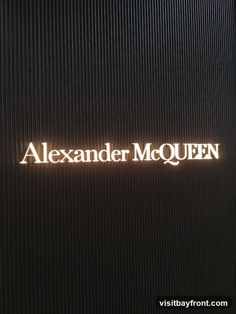 A close-up shot of the Alexander McQueen logo illuminated against a dark, ribbed background.