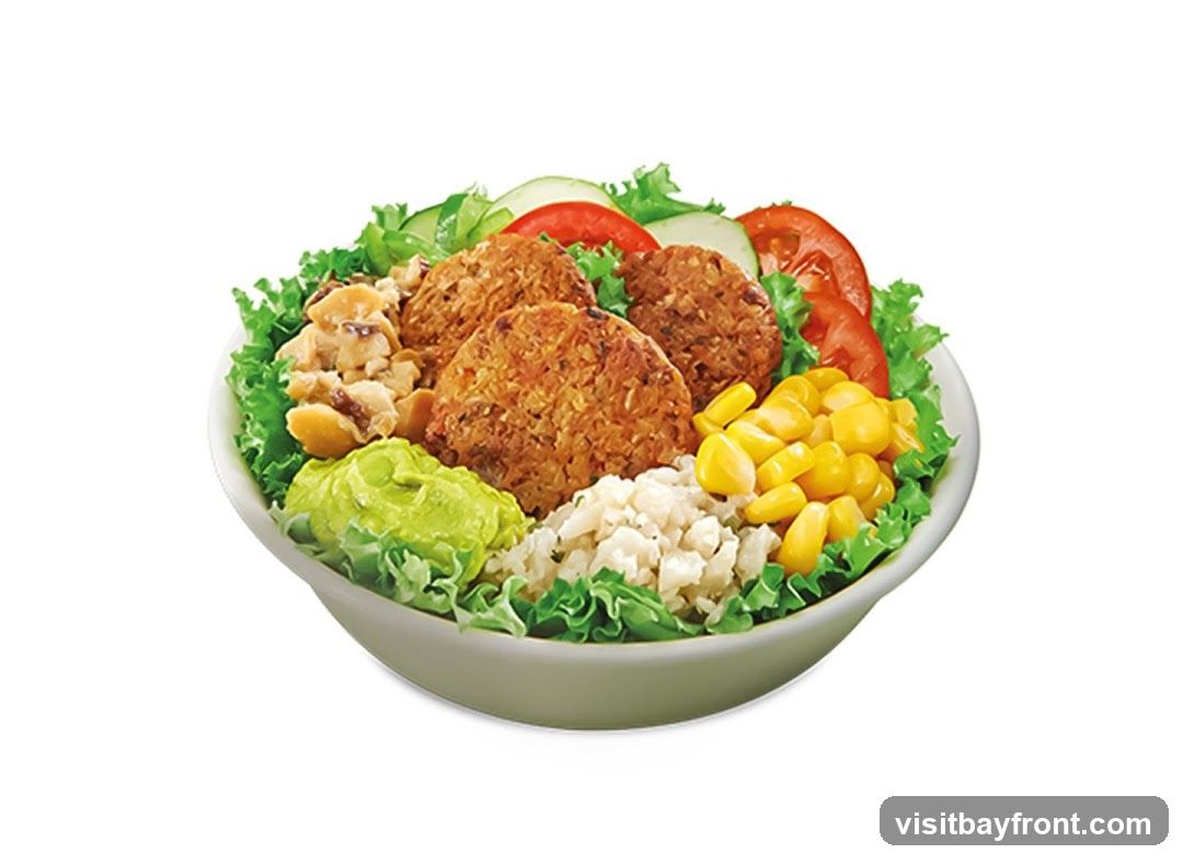 A close-up, isolated image of a Subway sandwich on a white background. The sandwich is made with a long, crusty bread roll filled with lettuce, tomato, cucumber, red onion, pickles, cheese, chicken, and bacon, topped with a creamy sauce.