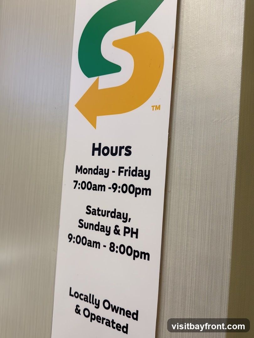 A sign displaying the operating hours for a Subway restaurant. The sign features the Subway logo and lists hours for weekdays and weekends/holidays. It also states "Locally Owned & Operated".