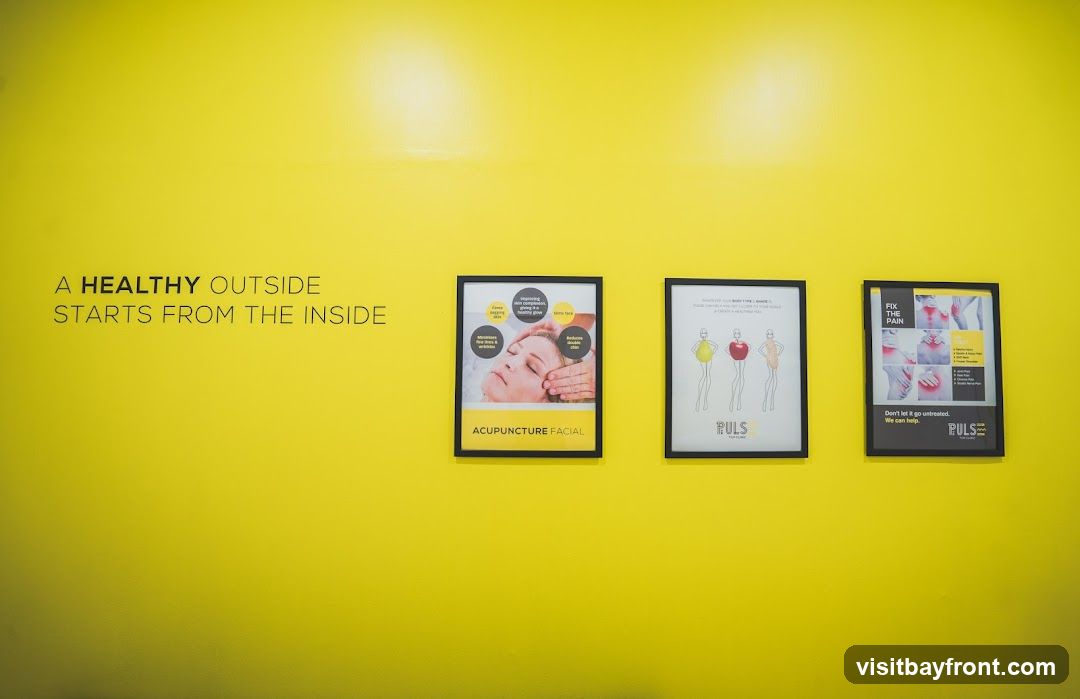 A bright yellow wall with a motivational quote and three framed posters. The quote reads "A HEALTHY OUTSIDE STARTS FROM THE INSIDE." The posters advertise "ACUPUNCTURE FACIAL," body shaping, and pain relief services, all branded with "PULS."