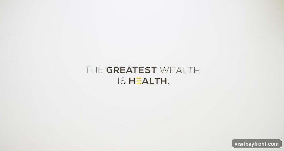 A minimalist graphic with the text "THE GREATEST WEALTH IS HEALTH." The word "HEALTH" has a stylized graphic element replacing the letter "A".