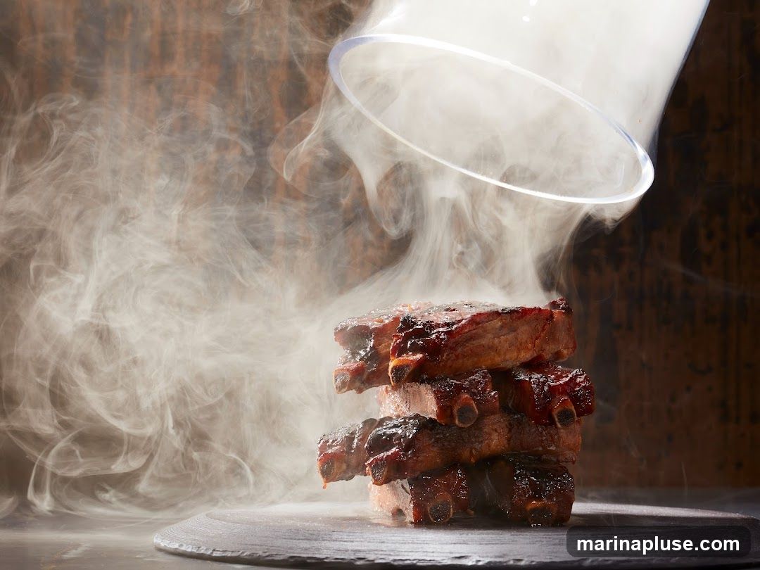A stack of smoked ribs, glazed with a dark sauce, is presented on a slate plate. Smoke billows around the ribs, creating a dramatic effect. A clear glass cloche is lifted, releasing more smoke. The background is a dark, textured wood.