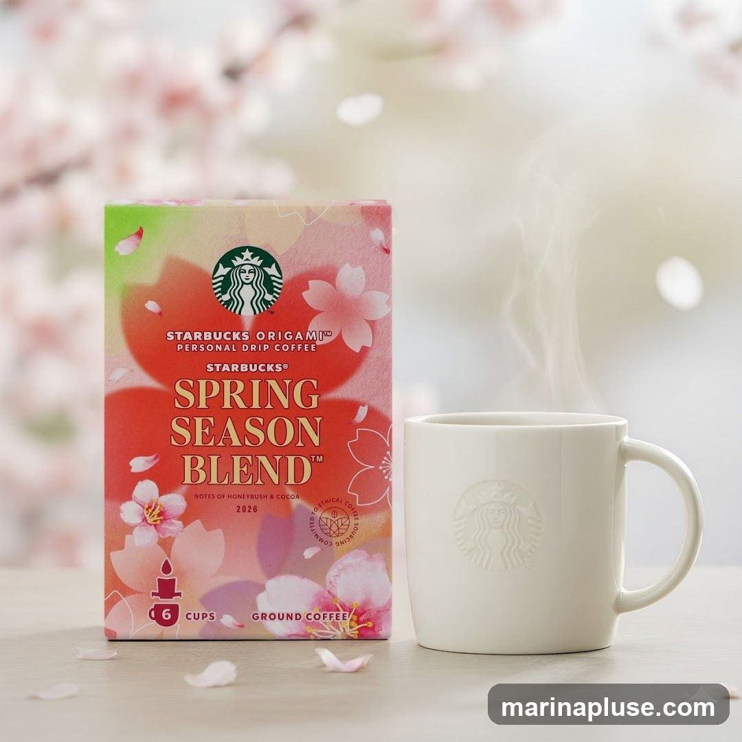 A box of Starbucks Origami Personal Drip Coffee, Spring Season Blend, is displayed next to a white mug with the Starbucks logo. The box features a pink and green floral design with cherry blossoms. The coffee blend notes are honeybush and cocoa. Steam rises from the mug.