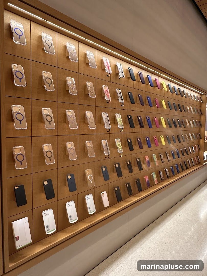 A wall display featuring numerous phone cases, primarily for iPhones, arranged in a grid. The cases are of various colors and designs, including clear cases with magnetic rings, solid colored cases, and some with straps. Some packaging for accessories is also visible on a lower shelf.
