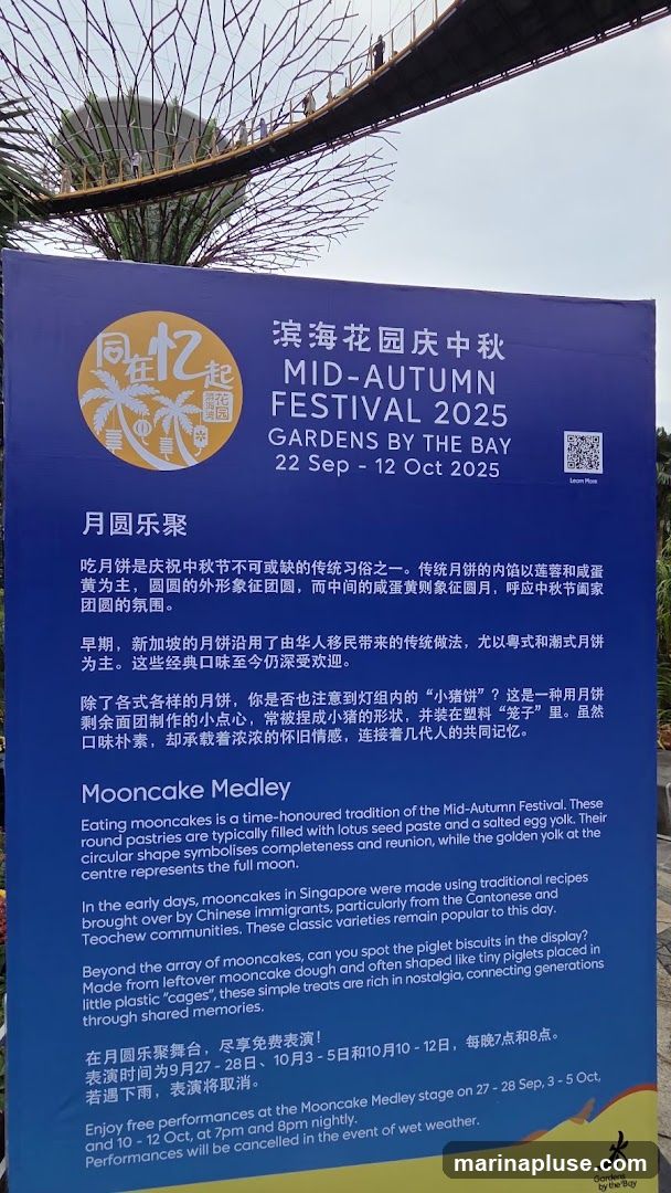 A sign announcing the Mid-Autumn Festival 2025 at Gardens by the Bay, running from September 22 to October 12. It describes the tradition of eating mooncakes, their symbolism, and the history of mooncakes in Singapore. It also highlights 'piglet biscuits' and mentions free performances at the Mooncake Medley stage on specific dates and times, with cancellations in case of rain.