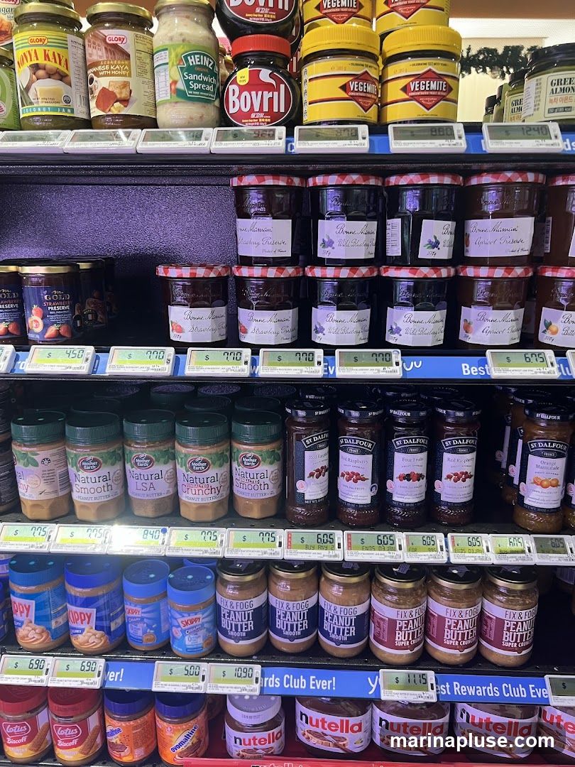 A shelf display of various jars of jams, preserves, sandwich spreads, peanut butters, and Nutella.