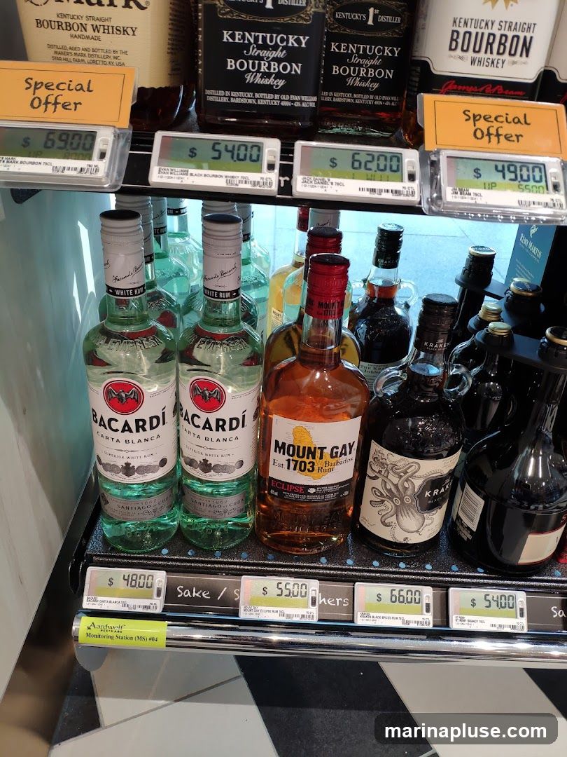 A selection of liquor bottles, including Bacardi Carta Blanca, Mount Gay Eclipse Rum, and Kraken Black Spiced Rum, are displayed on shelves. Price tags are visible below some of the bottles, with some indicating "Special Offer." Bottles of Kentucky Straight Bourbon Whiskey are visible on the top shelf.