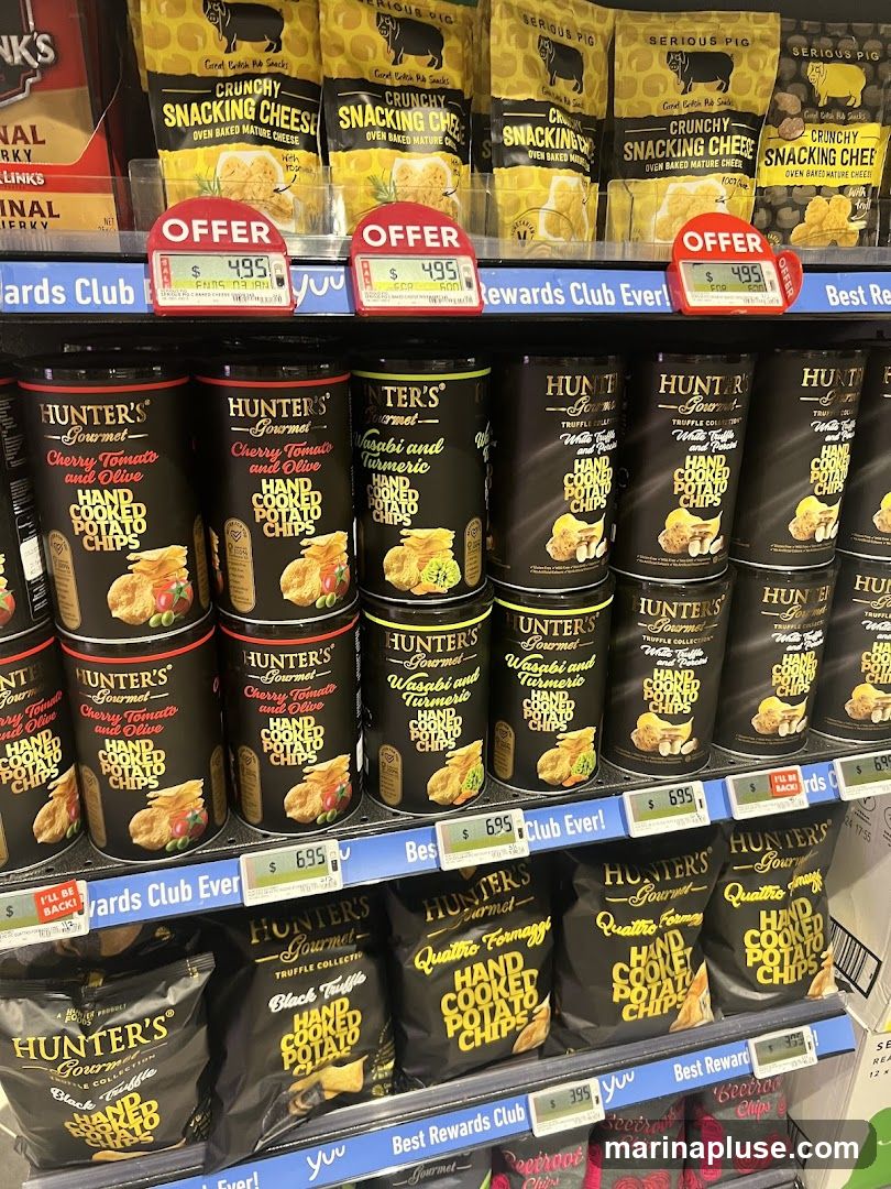 A retail display shelf filled with various bags and canisters of potato chips and other snacks. Prominent brands include "Hunter's Gourmet" and "Serious Pig". Several "Offer" signs are visible, indicating discounted prices.