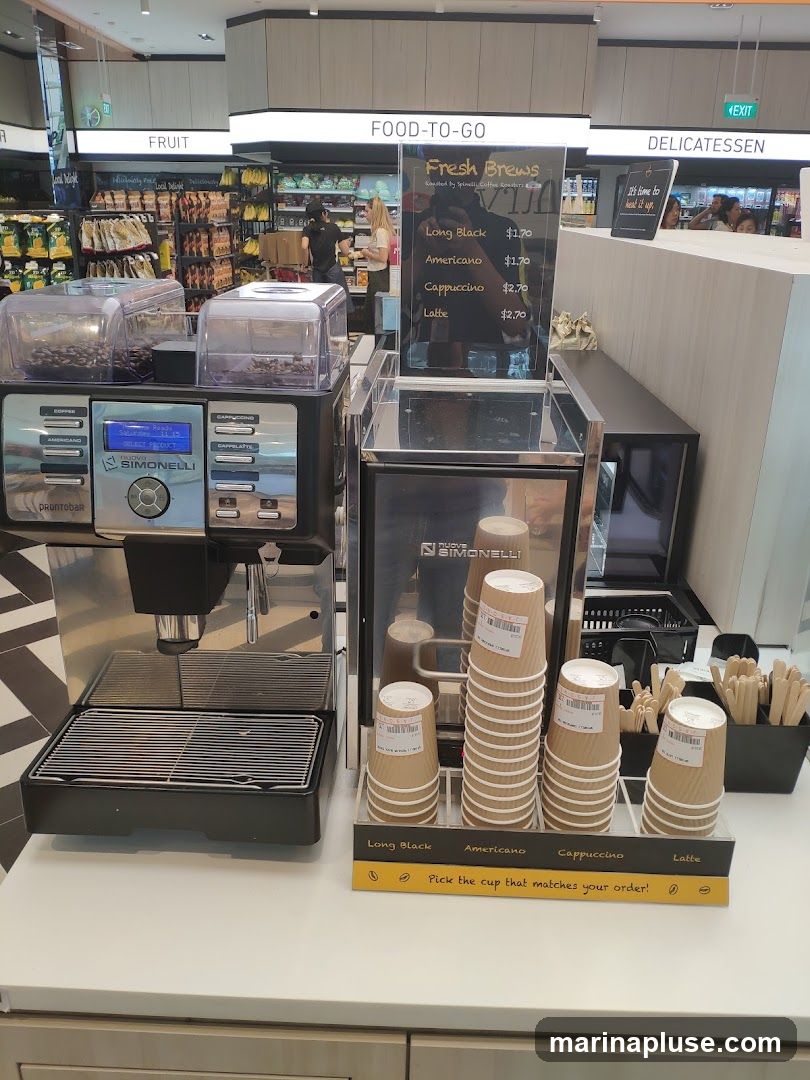 A coffee machine with various cups and a menu board displaying coffee options and prices. The background shows a store with shelves stocked with food items.