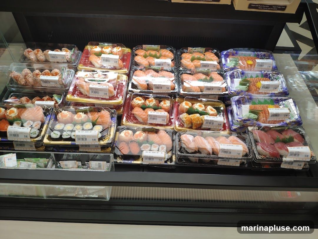 A refrigerated display case filled with various pre-packaged sushi sets. The sets include salmon nigiri, tuna nigiri, salmon sashimi, and maki rolls. Some sets are labeled with prices and brand names.