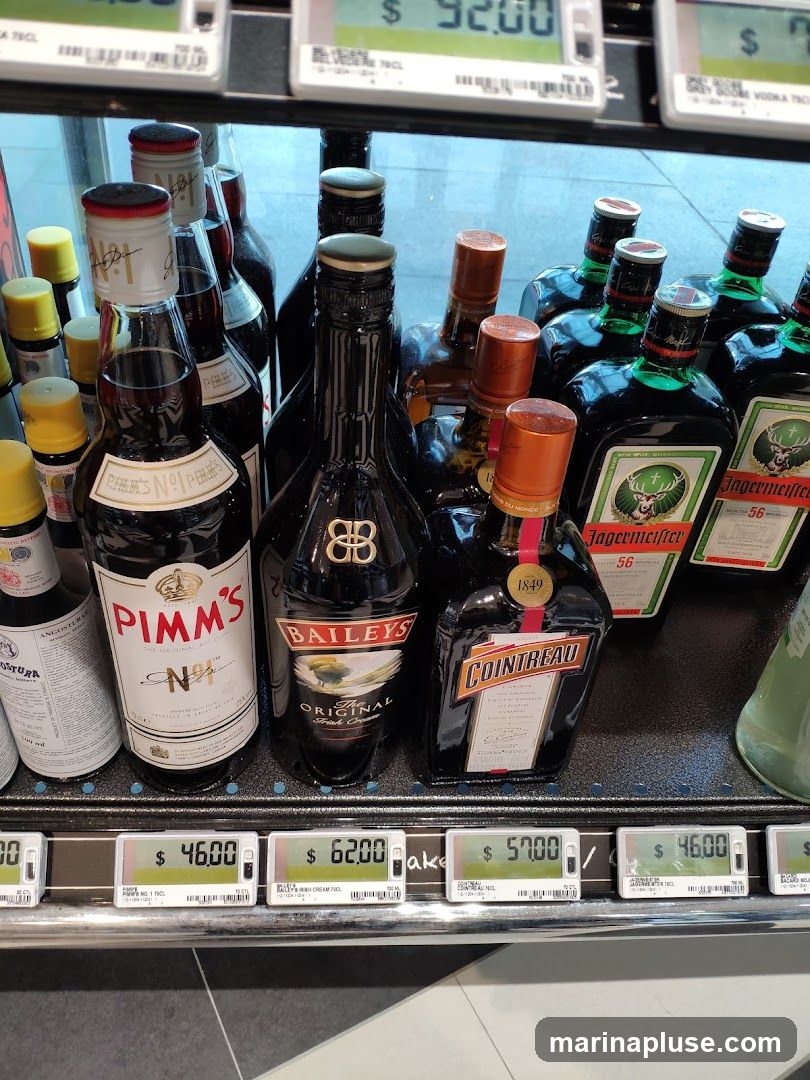 A display of various liquor bottles, including Pimm's No. 1, Baileys Original Irish Cream, Cointreau, and Jägermeister, arranged on shelves with price tags.