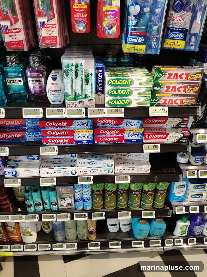A retail shelf displaying a variety of oral care products, including toothbrushes, toothpaste, mouthwash, and denture cleaners. Also visible are hair care products, hand soaps, and skin care items. Prices are displayed below many of the products.