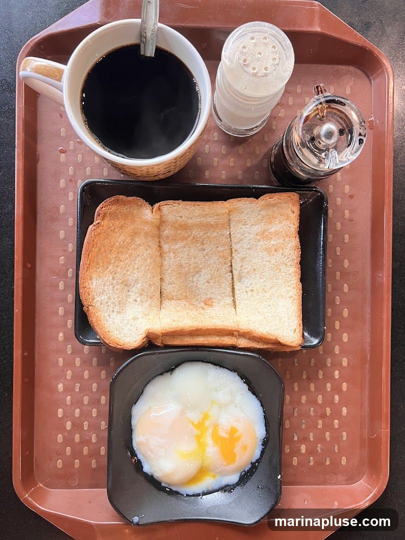 A tray with a cup of black coffee, a stack of toast, and two soft-boiled eggs. There are also salt and pepper shakers and a small bottle of soy sauce.