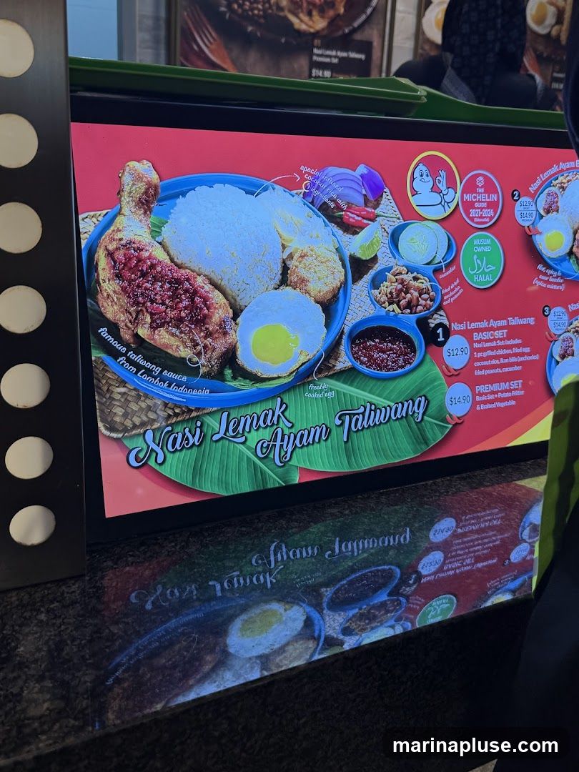 A digital menu board displaying Nasi Lemak Ayam Taliwang with various set options. The menu features images of the dish and its components, along with prices and descriptions. It also includes Michelin Guide and Halal certifications.