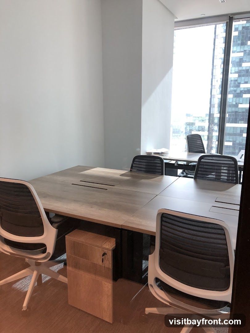 A modern office meeting room with a large wooden table and several mesh chairs. A filing cabinet is placed under the table. The room has large windows with a view of a city skyline.