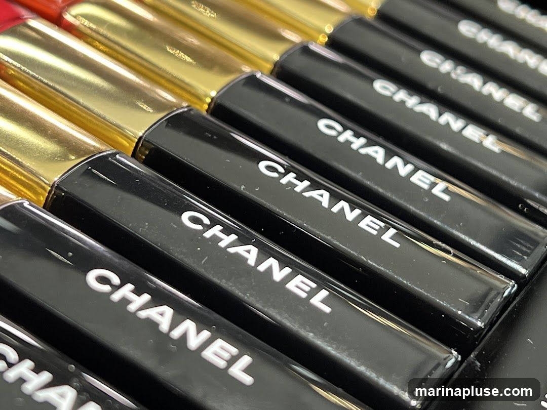 A close-up, angled view of multiple black lipstick tubes with gold caps, each bearing the white 'CHANEL' logo. The lipsticks are arranged in rows, suggesting a display or collection.